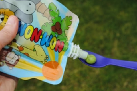 Nom Nom kids reusable yogurt pouch with pea puree on a spoon
