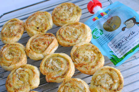 Nom Nom kids reusable pouch with vegetable puree next to homemade hidden vegetable and cheese pinwheels
