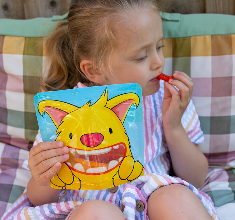 child eating red pepper sticks from a Nom Nom kids reusable snack bag
