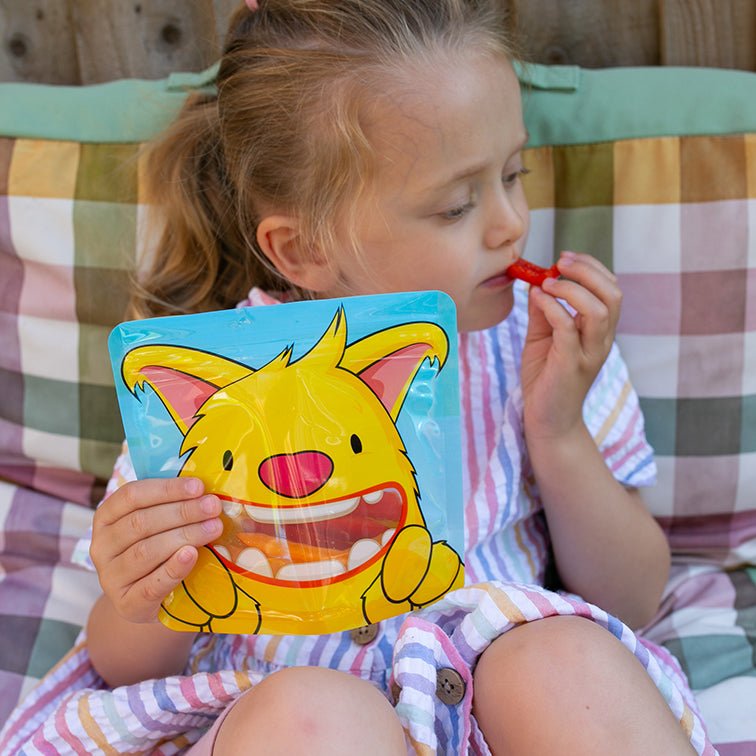 child eating red pepper sticks from a Nom Nom kids reusable snack bag