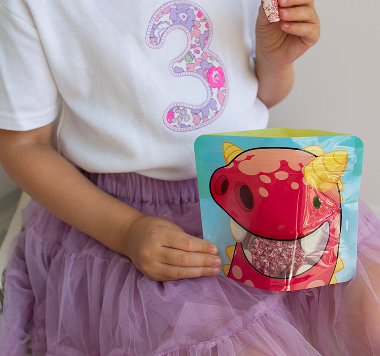 child eating flavoured rice cakes from a Nom Nom kids reusable snack pouch