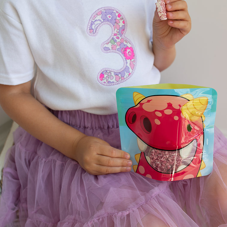 child eating flavoured rice cakes from a Nom Nom kids reusable snack pouch