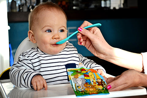 baby eating homemade puree from a Nom Nom kids reusable yogurt pouch