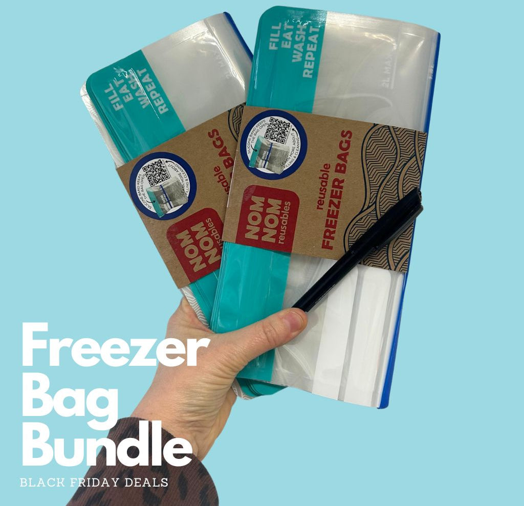 a hand holding 2 packs of Nom Nom Reusable Freezer bags and a pen