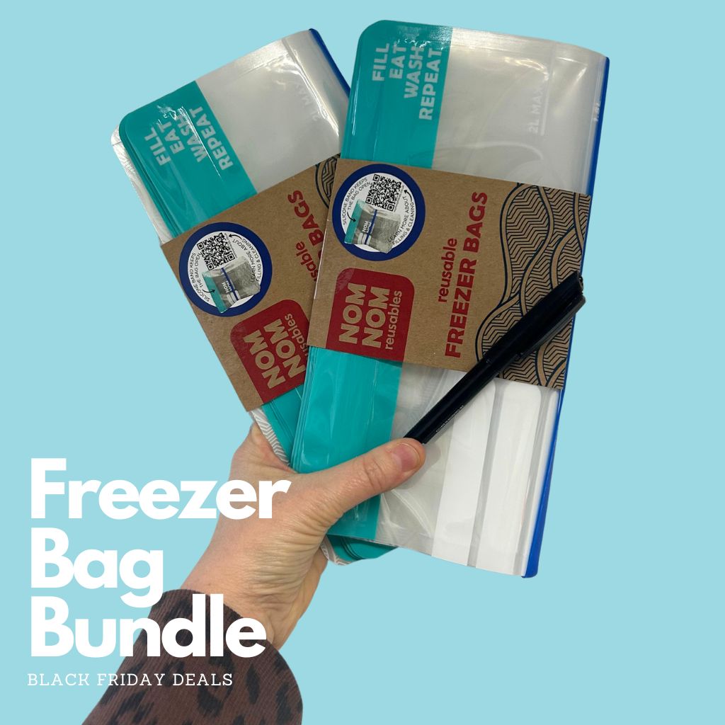 a hand holding 2 packs of Nom Nom Reusable Freezer bags and a pen