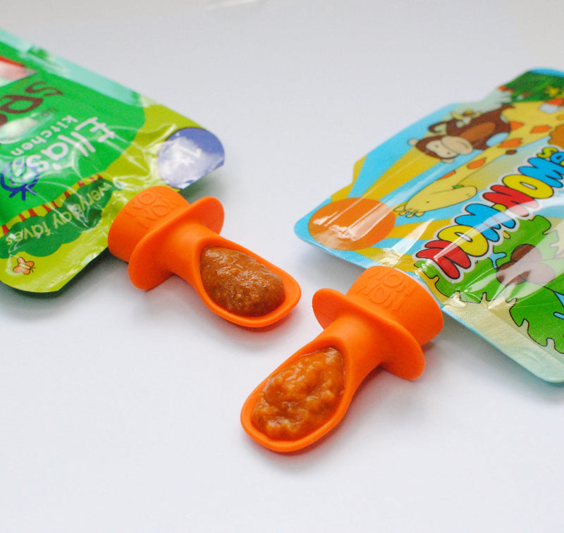 silicone pouch spoon fitted onto an Ella's Kitchen baby food pouch and a Nom Nom Kids reusable food pouch