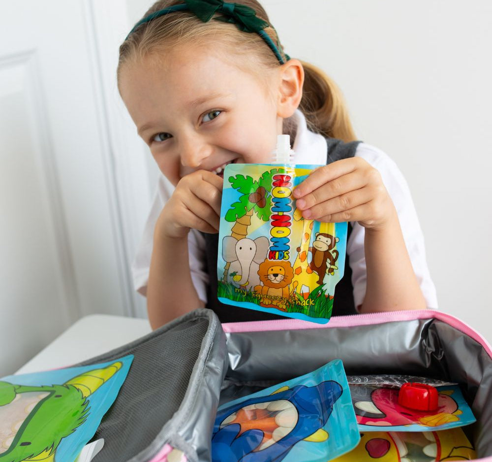 child behind lunch box packed with Nom Nom kids reusable pouches filled with snacks.