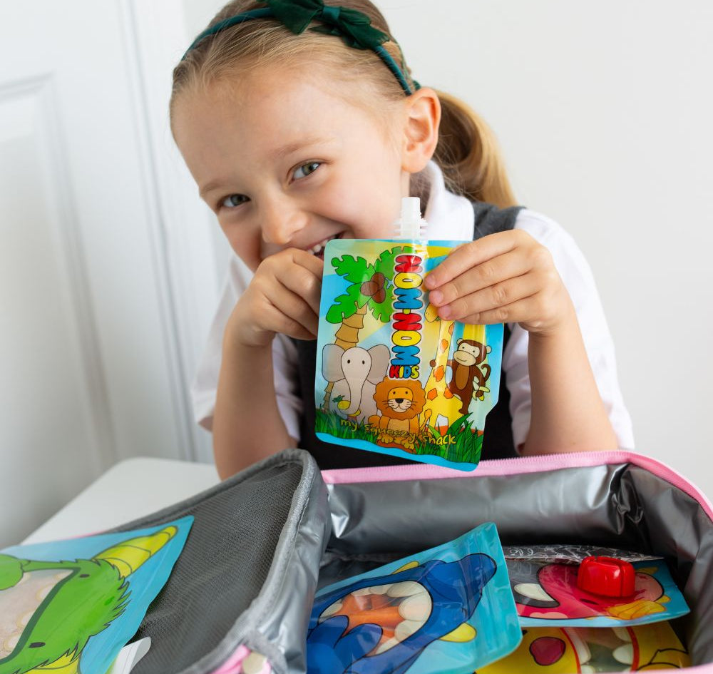 child behind lunch box packed with Nom Nom kids reusable pouches filled with snacks.