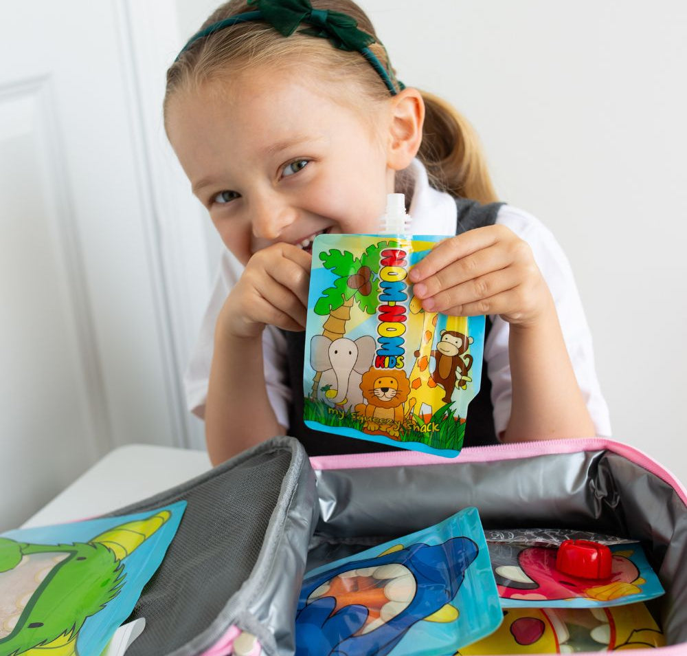 child behind lunch box packed with Nom Nom kids reusable pouches filled with snacks.