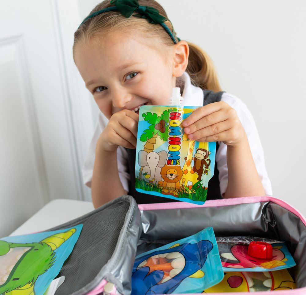 child behind lunch box packed with Nom Nom kids reusable pouches filled with snacks.
