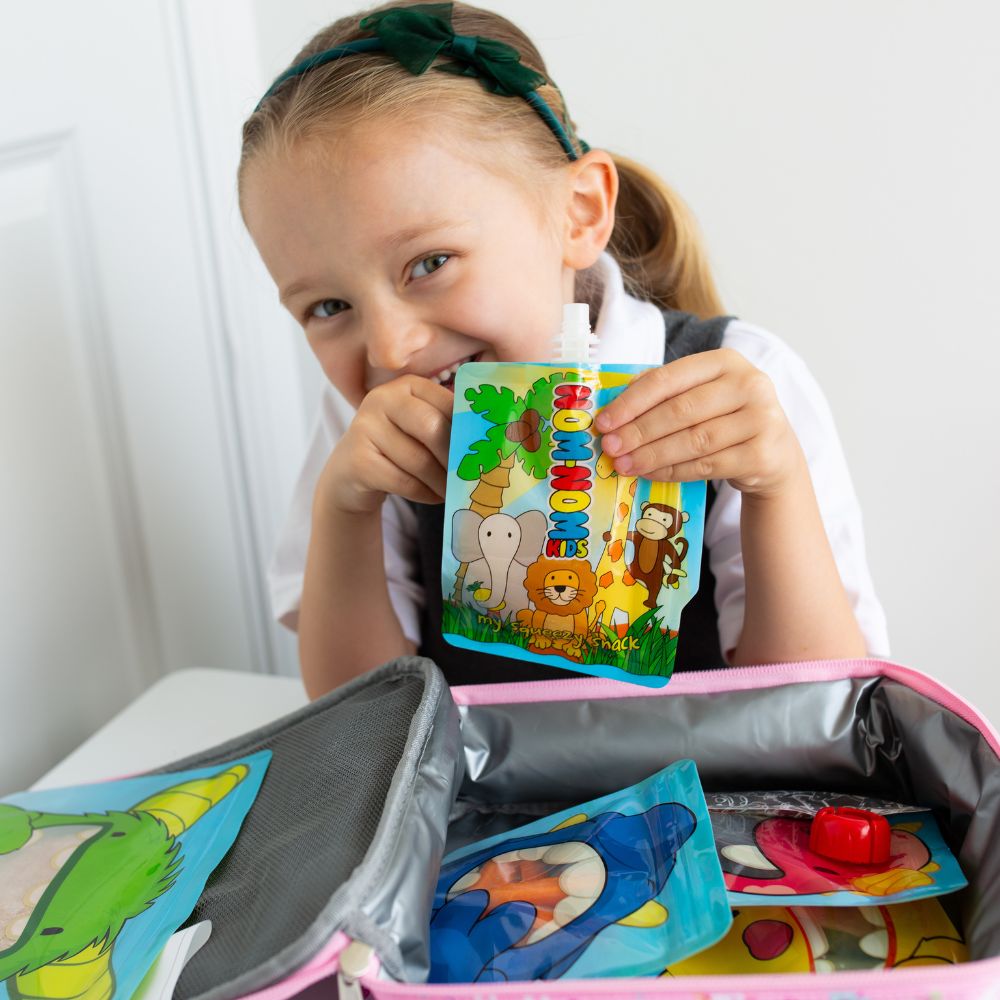 child behind lunch box packed with Nom Nom kids reusable pouches filled with snacks.