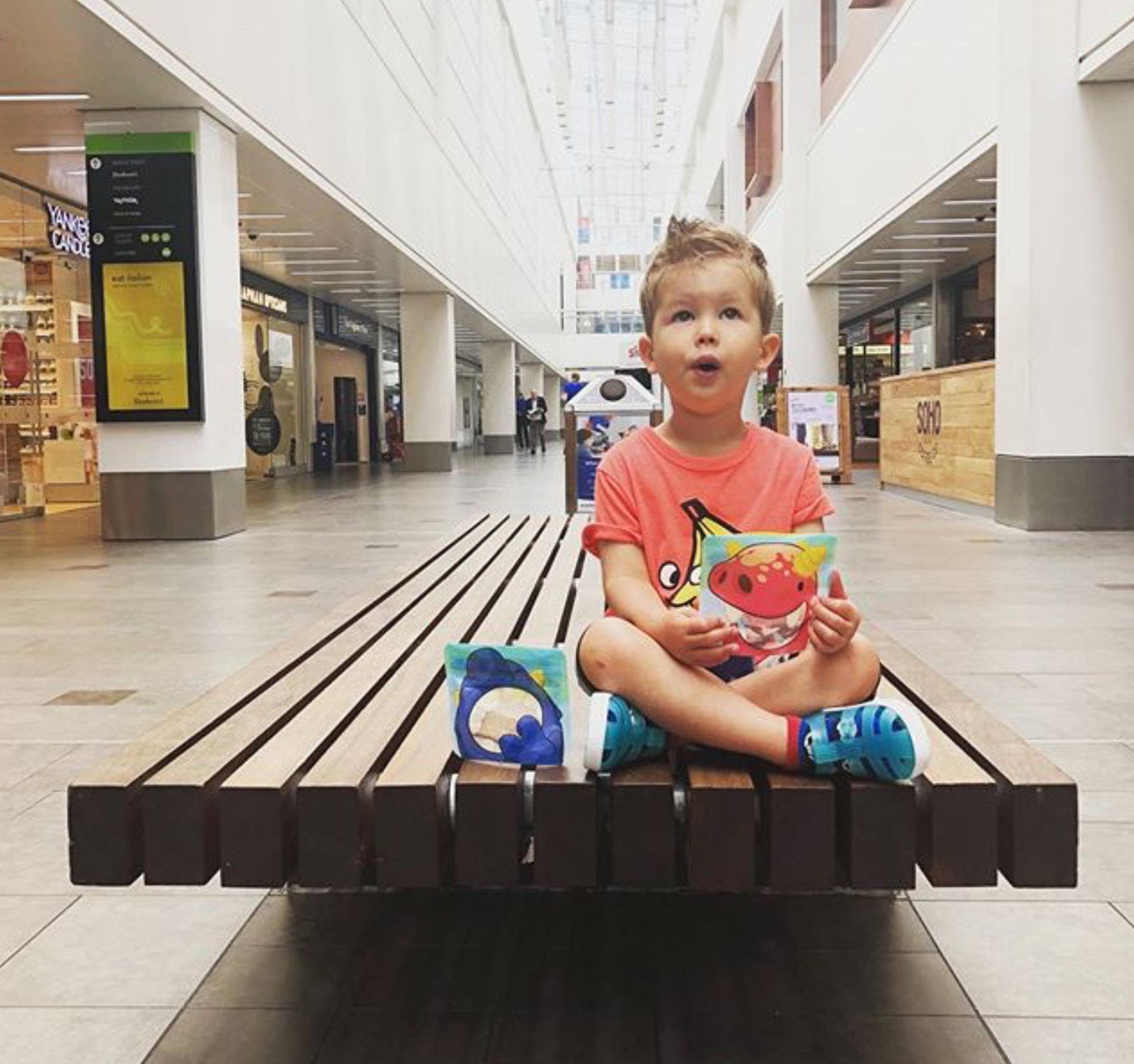 child sat on a bench eating from a Nom Nom kids snack bag