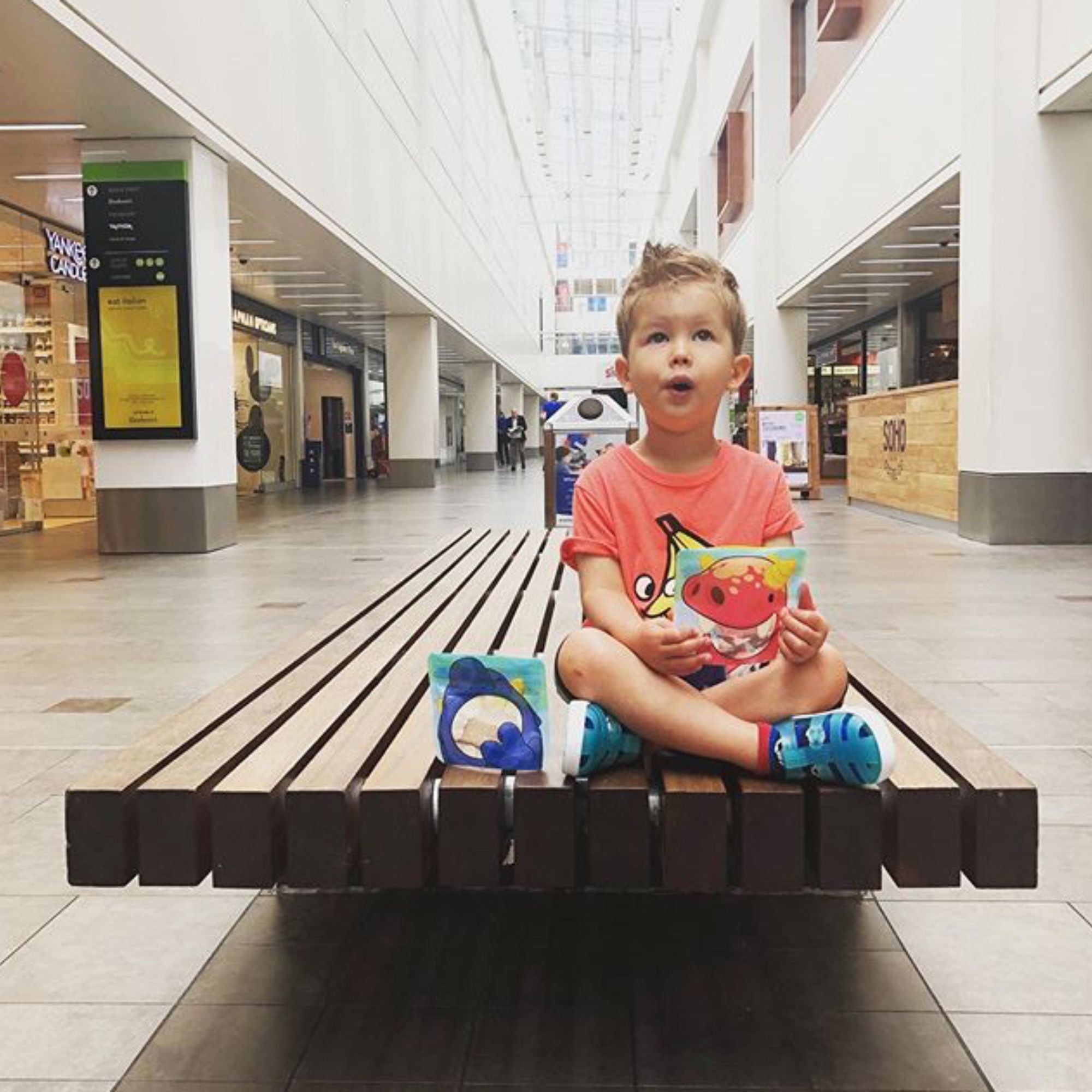 child sat on a bench eating from a Nom Nom kids snack bag