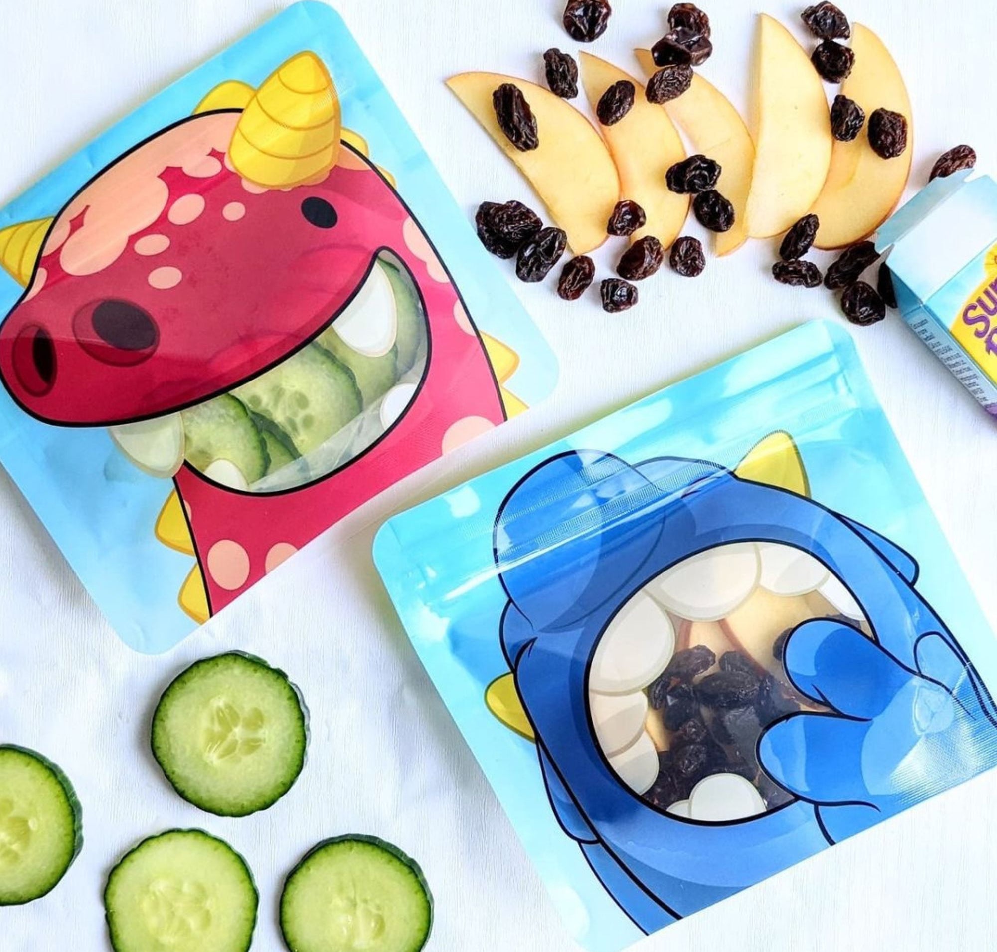 Nom Nom kids reusable snack bags filled with cucumber, apples and raisins.