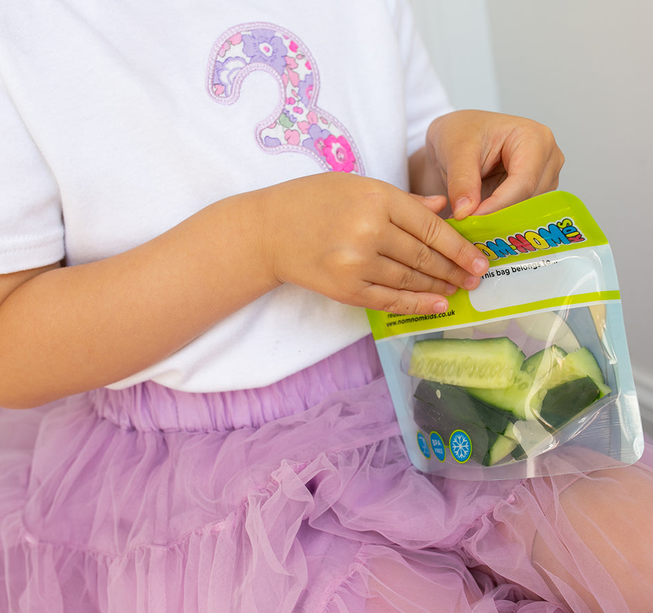 child eating from a Nom Nom kids reusable snack bag