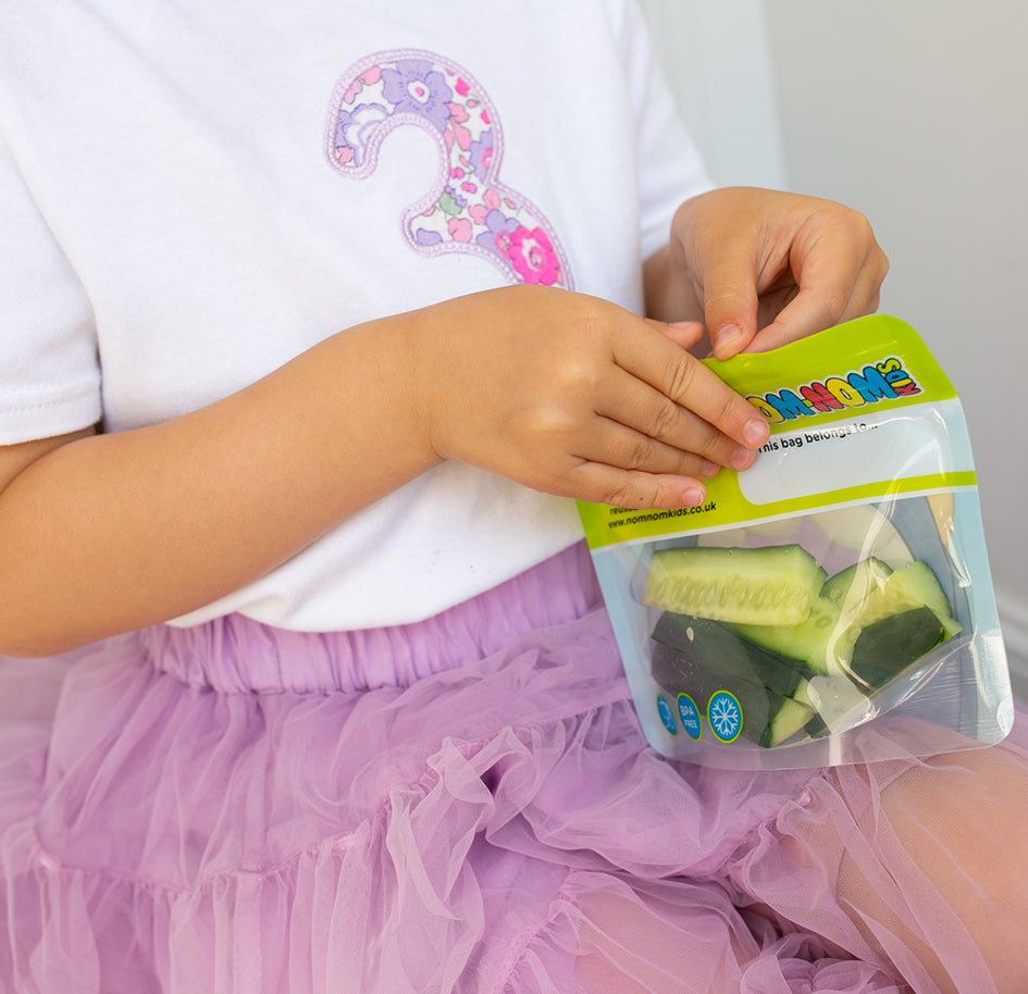 child eating from a Nom Nom kids reusable snack bag