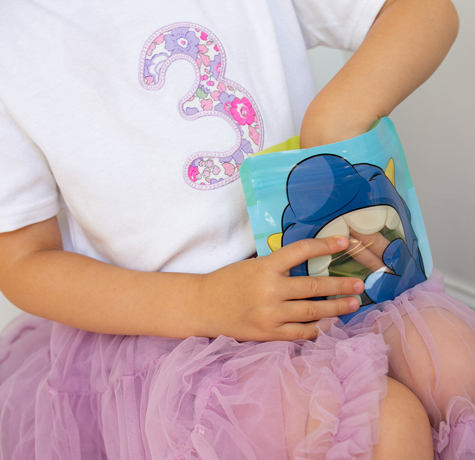 Child eating cucumber from a Nom Nom kids blue monster reusable snack bag