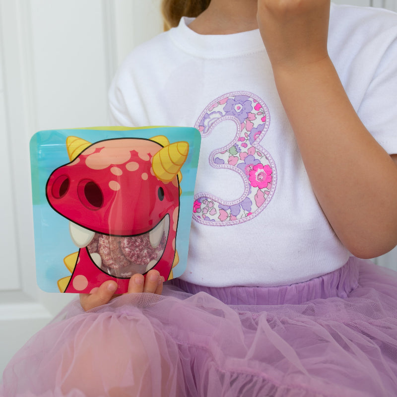 3 year old girl eating snacks from a nom nom kids reusable snack bag