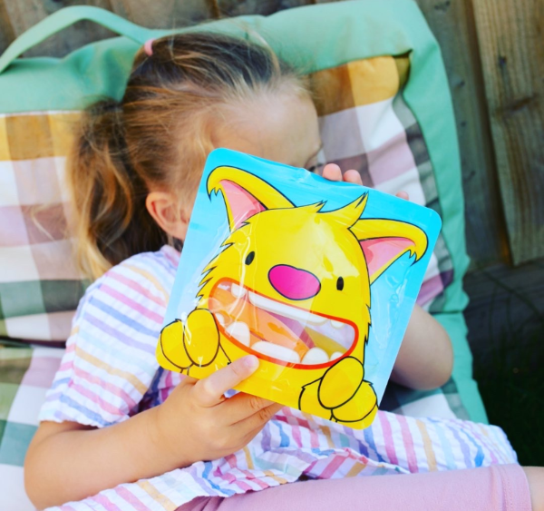 little girl holding a reusable snack bag filled with carrots for snack
