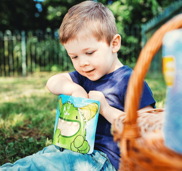 little boy reaching inside a Nom Nom kids sandwich bag