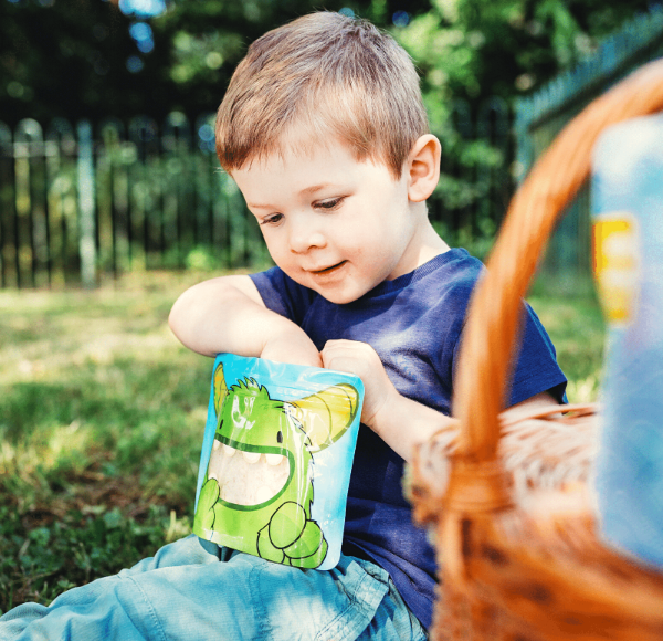 little boy reaching inside a Nom Nom kids sandwich bag