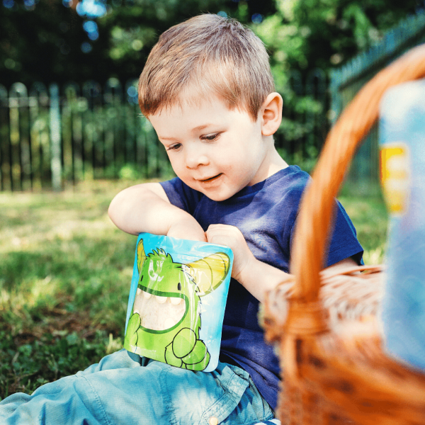 little boy reaching inside a Nom Nom kids sandwich bag