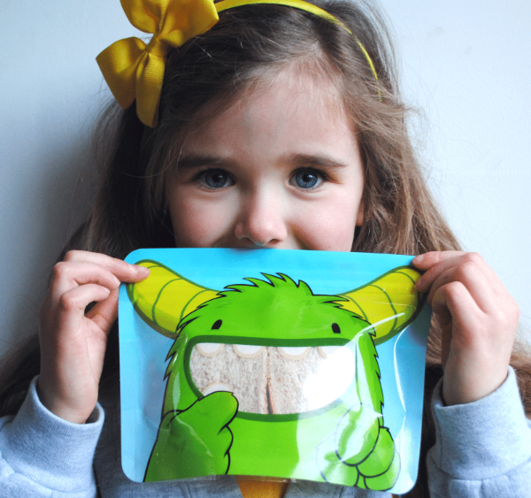 little girl holding Nom Nom kids sandwich bag