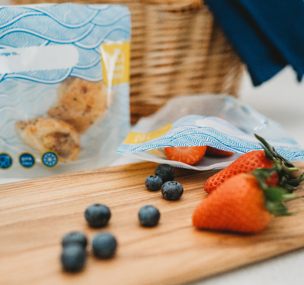 nom nom reusables wave design snack bags being filled with strawberries and blueberries