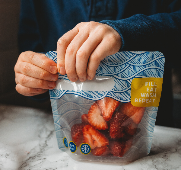 child sealing up a snack bag containing strawberries