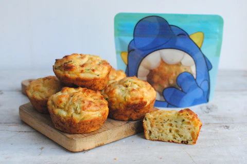homemade carrot and courgette cheesy muffins in front of a blue Nom Nom kids reusable snack bag 