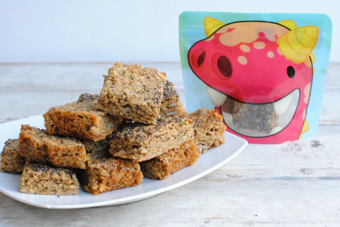 homemade seeded flapjacks in front of a Nom Nom kids red monster reusable snack bag 