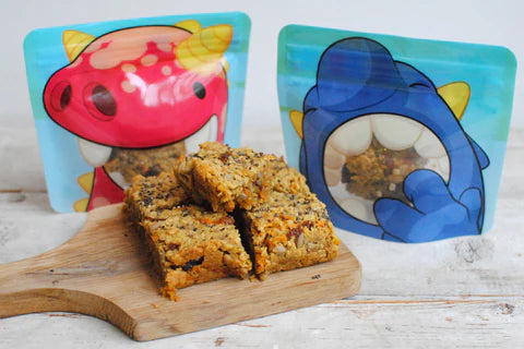 homemade carrot cake flapjacks in front of two Nom Nom kids snack bags 