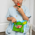 child eating watermelon slice from Nom Nom kids reusable snack pouch. 