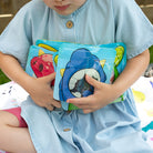 child holding a collection of Nom Nom kids reusable snack bags. 