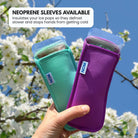 Two ice pop holders, one green and one purple, held by a hand with a cherry blossom background.