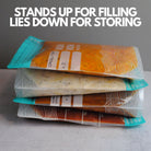 Nom Nom clear reusable freezer bags filed with food laying down for appropriate storage in the freezer 