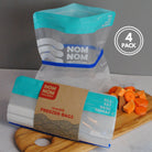 Nom Nom clear reusable freezer bags held open with a blue rubber band for easier filling 