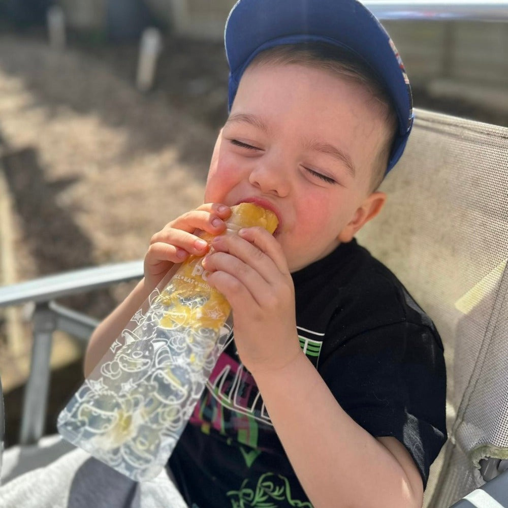 A toddler boy eating an ice pop with his eyes closed and a happy expression