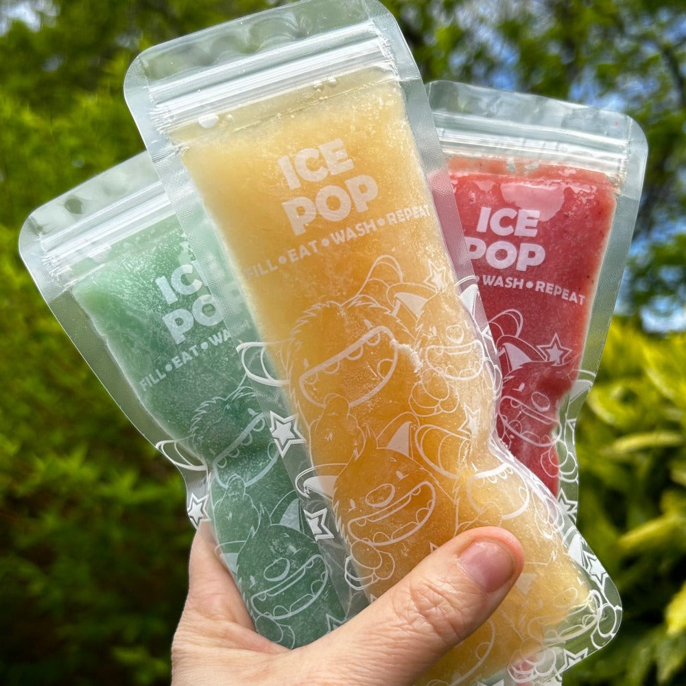 3 ice pops being held up against a backdrop of trees
