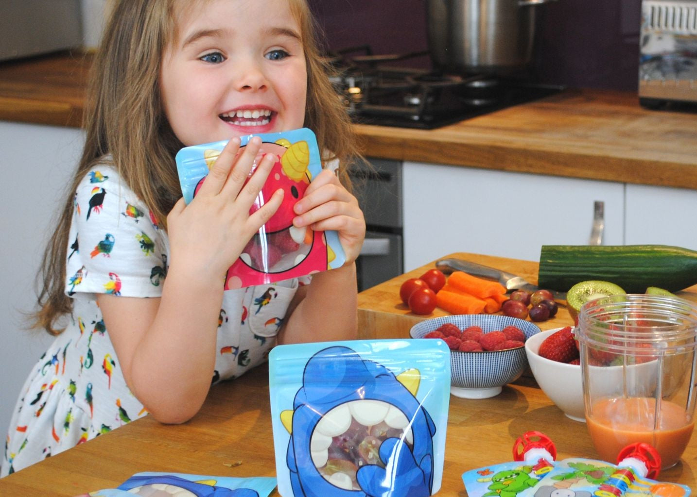 3 year old girl sat at the kitchen work top with snack bags full of fresh food
