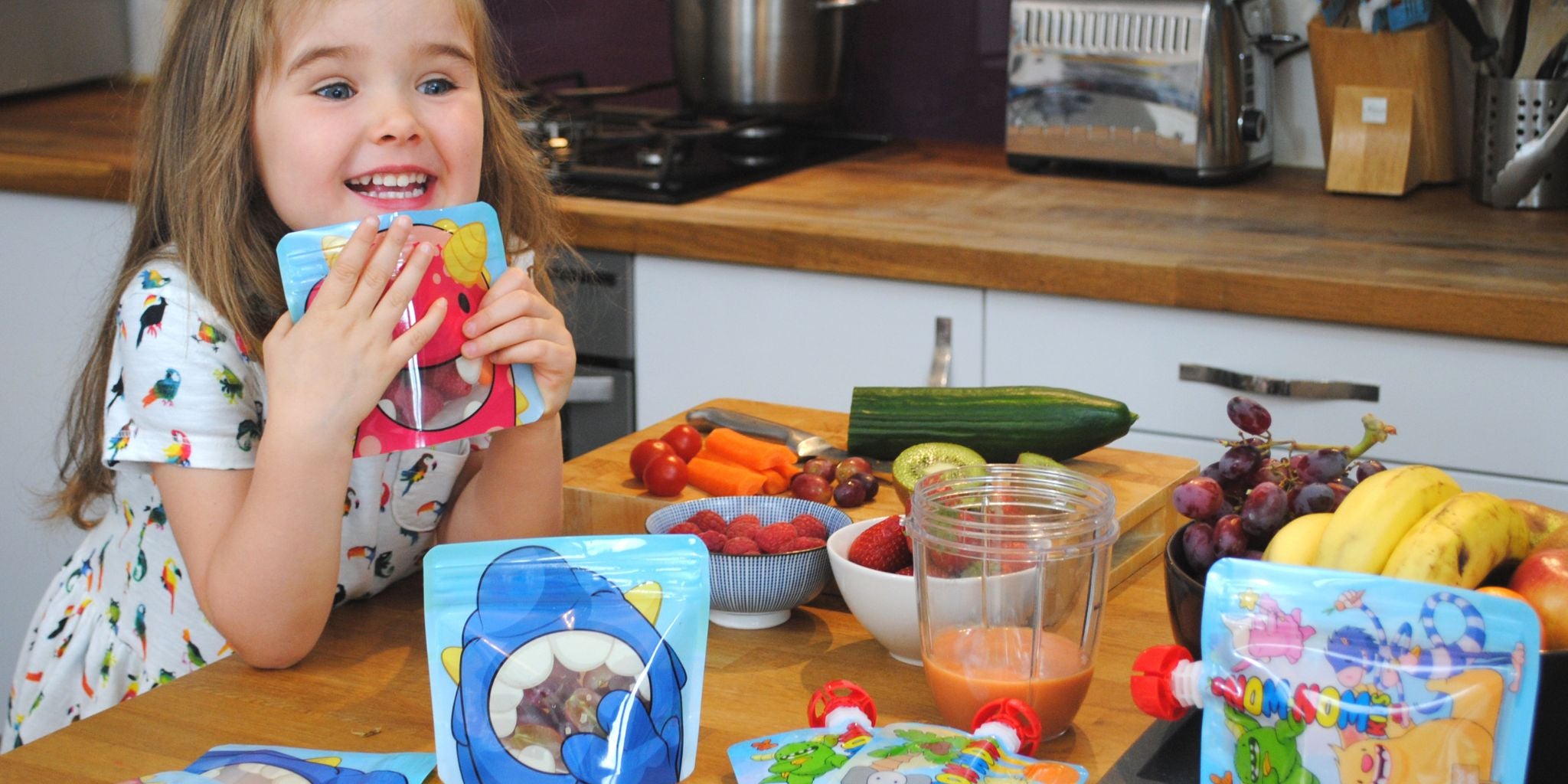 3 year old girl sat at the kitchen work top with snack bags full of fresh food