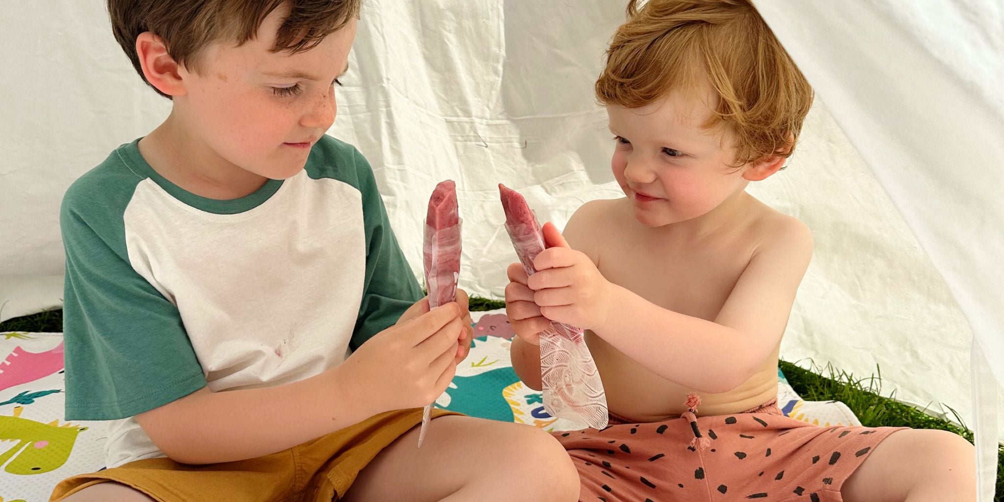 two children using the Nom Nom kids reusable ice pop bags filled with a homemade ice pop mixture 