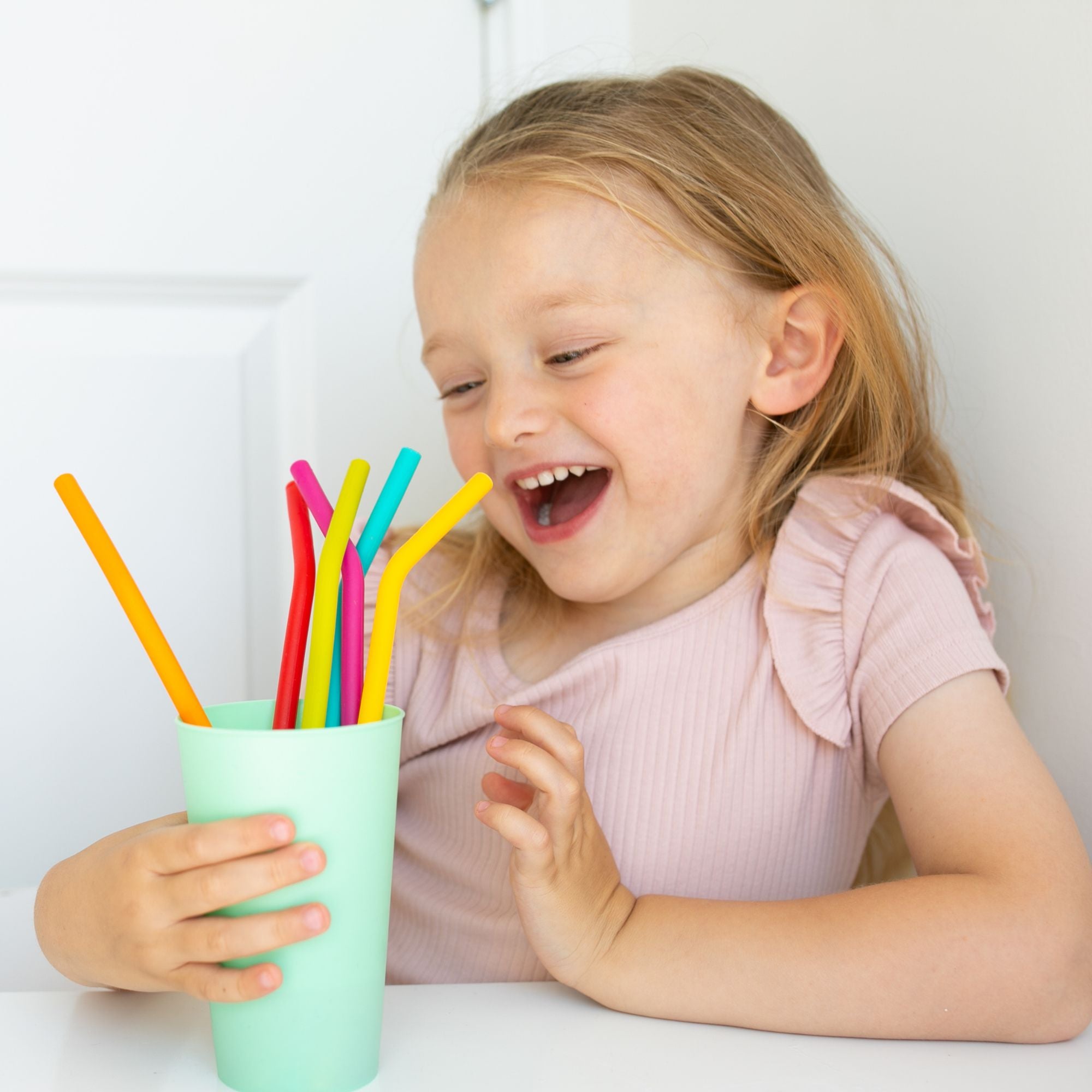 child holding a cup of Nom Nom kids reusable silicone straws 
