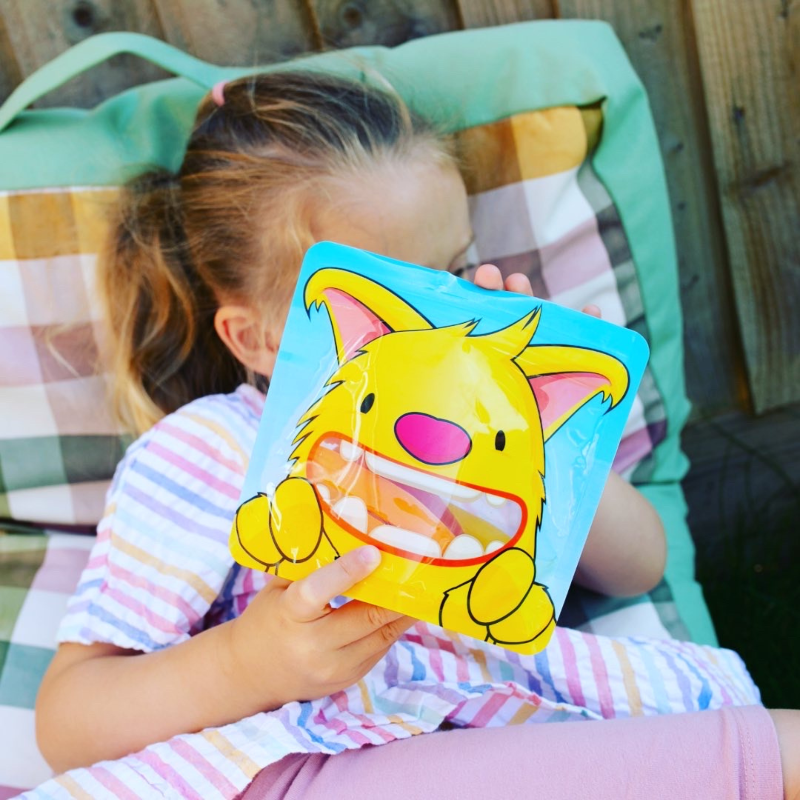 little girl holding a reusable snack bag filled with carrots for snack