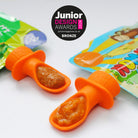 2 silicone pouch spoons. 1 attached to an Ella's Kitchen pouch and 1 attached to a Nom Nom Kids pouch with a Junior design award badge