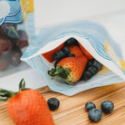 Nom Nom kids reusable snack bag filled with strawberries and bluberries. 