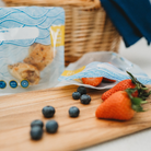 nom nom reusables wave design snack bags being filled with strawberries and blueberries